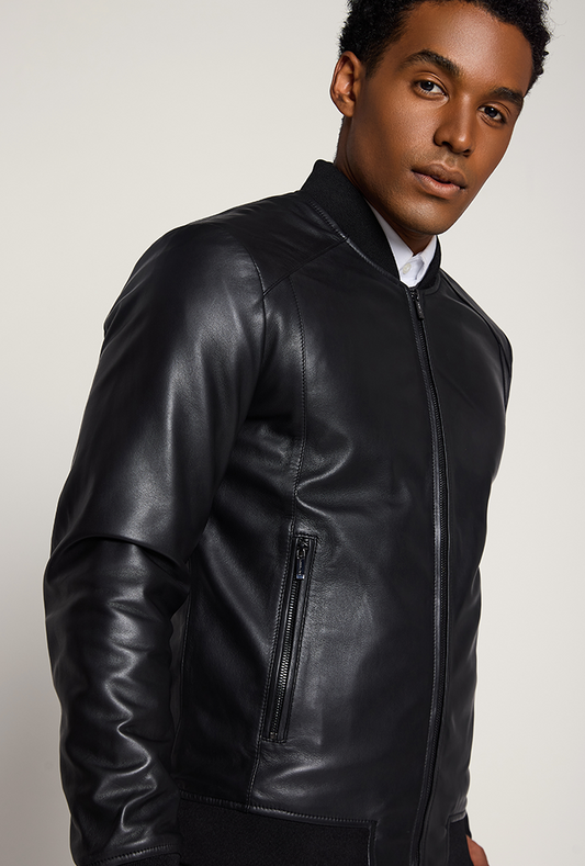 Men’s black genuine lambskin leather bomber jacket featuring side pockets, ribbed cuffs, collar and hem, front zip closure, and a lightweight, tailored fit.