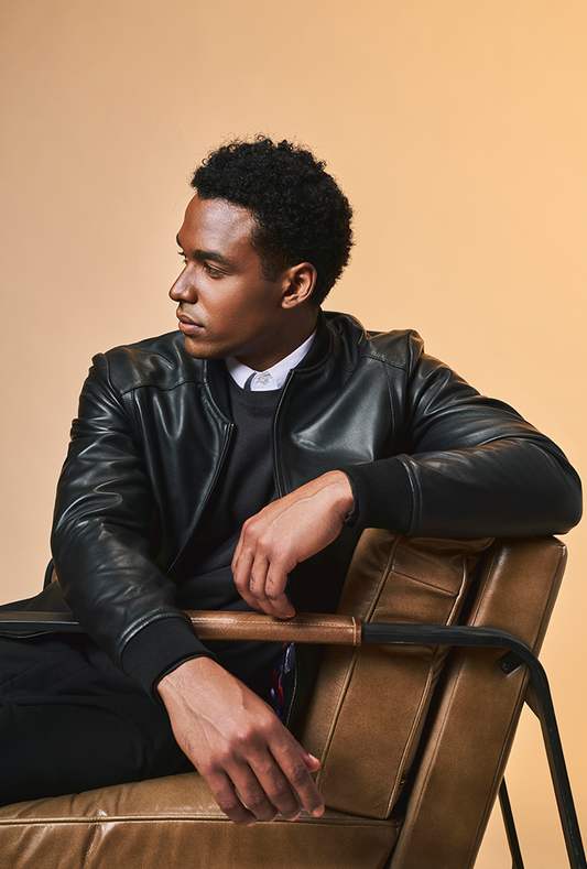 Men’s black genuine lambskin leather bomber jacket featuring side pockets, ribbed cuffs, collar and hem, front zip closure, and a lightweight, tailored fit.