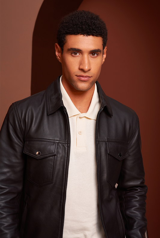 Men’s black genuine lambskin leather trucker jacket featuring chest pockets with flap closures, front zip closure, and a lightweight, tailored fit.
